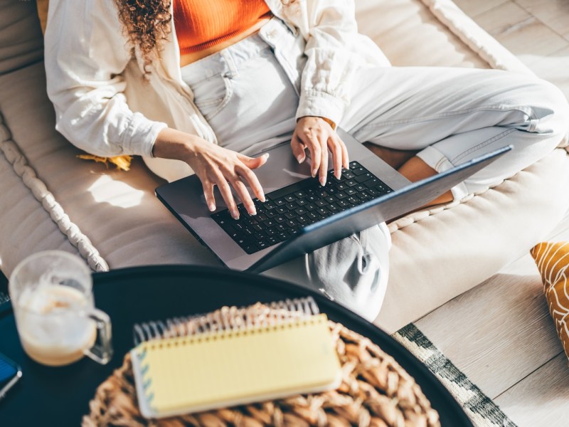 Junge Frau arbeitet mit Laptop im Wohnzimmer.