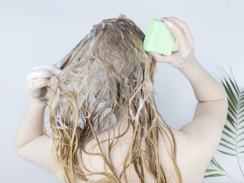 Frau wäscht sich die Haare mit festem Shampoo
