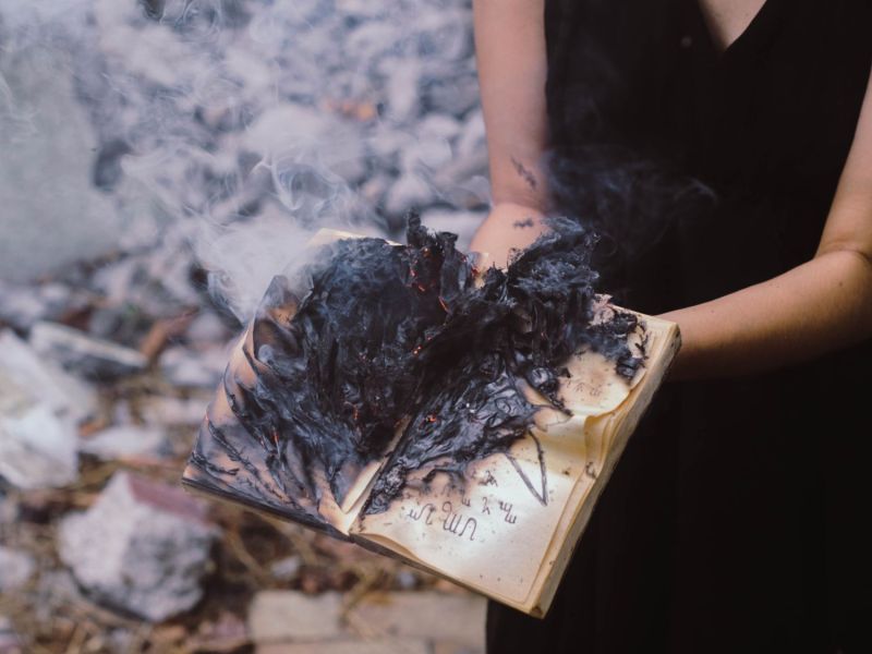 Frau hält brennendes Buch in der Hand zu den Rauchnächten Bedeutung