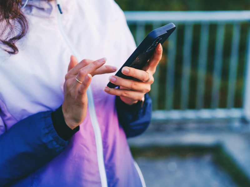 Eine Frau hält ihr Handy in der Hand.