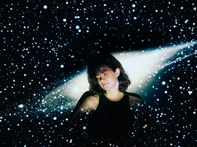 Frau wird angeleuchtet vor einem Sternenhimmel