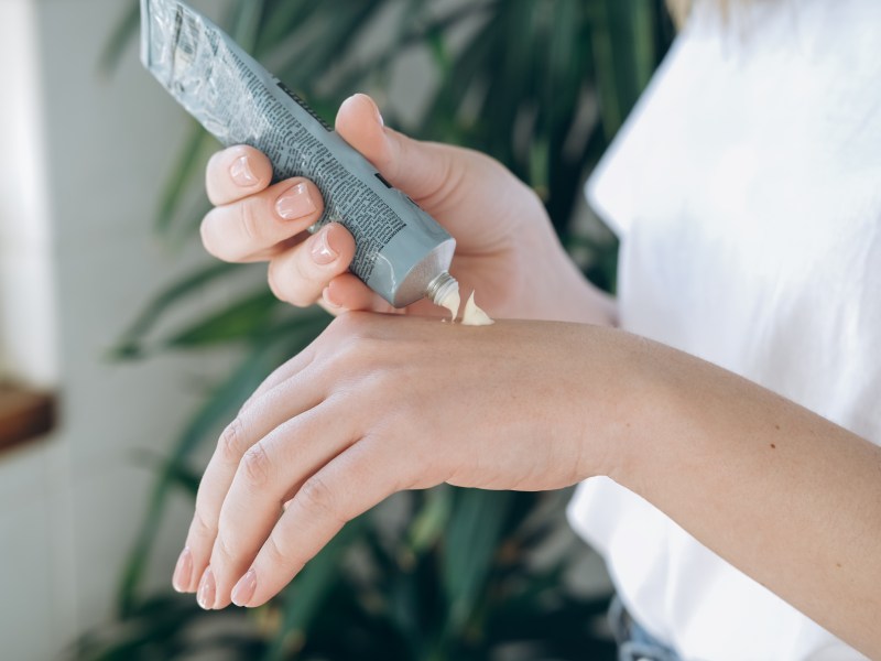 Frau nutzt Handcreme auf dem Handrücken