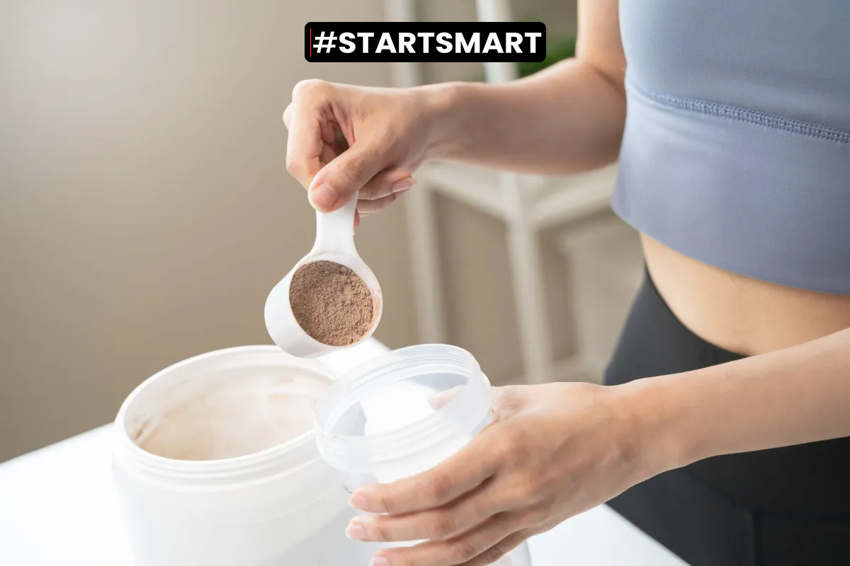 Frau gibt einen Scoop Proteinpulver in einen Shaker