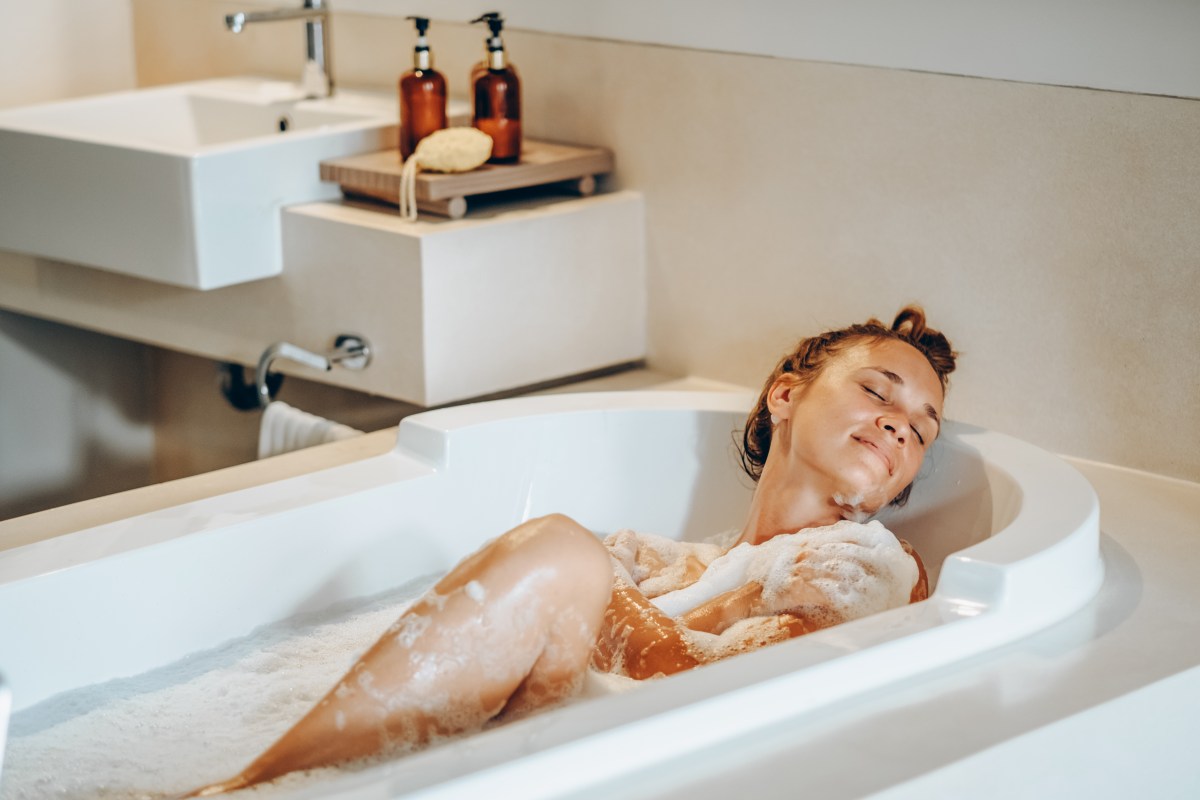 Frau liegt in der Badewanne mit Duschschaum