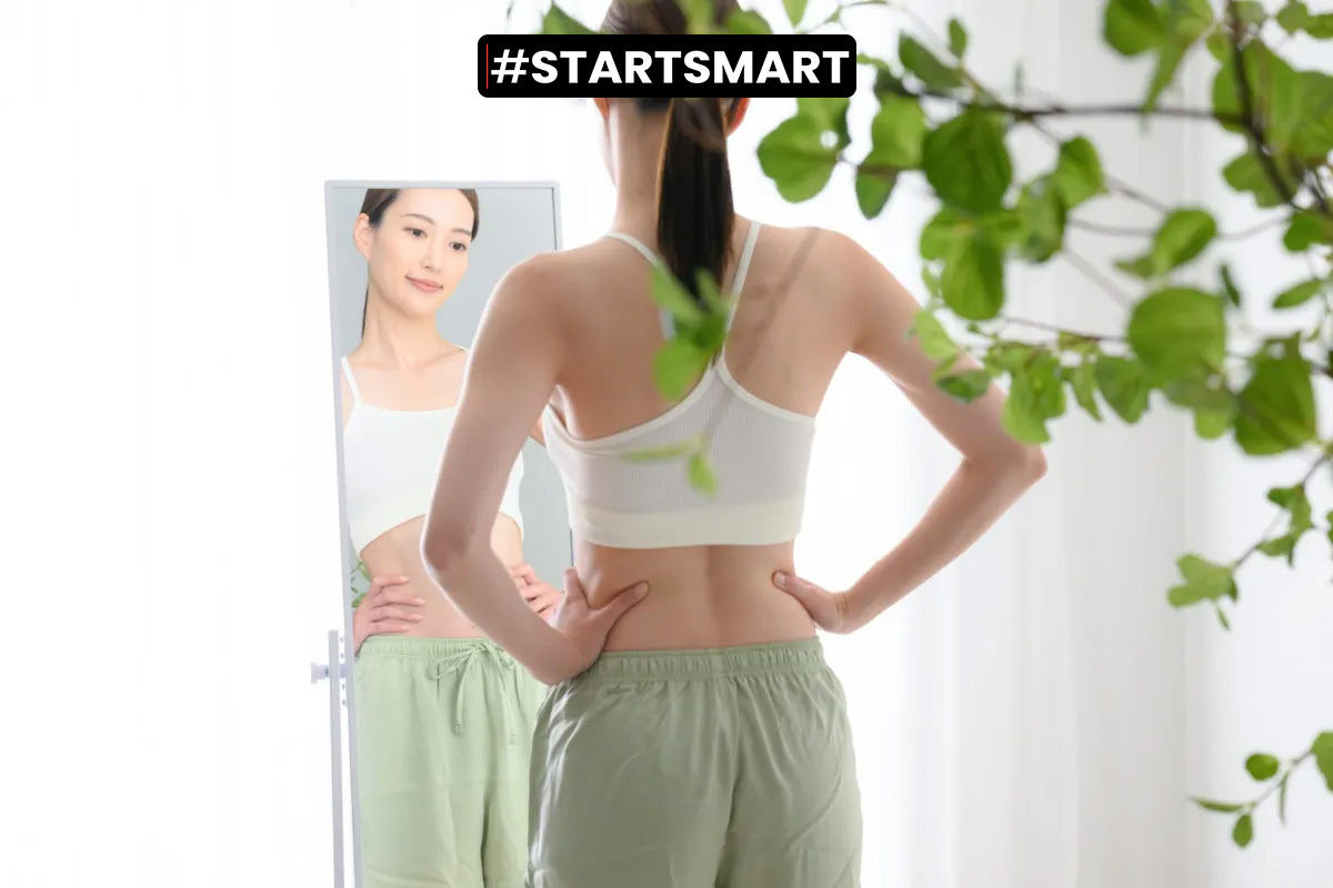 Frau in Fitnesskleidung betrachtet sich im Spiegel